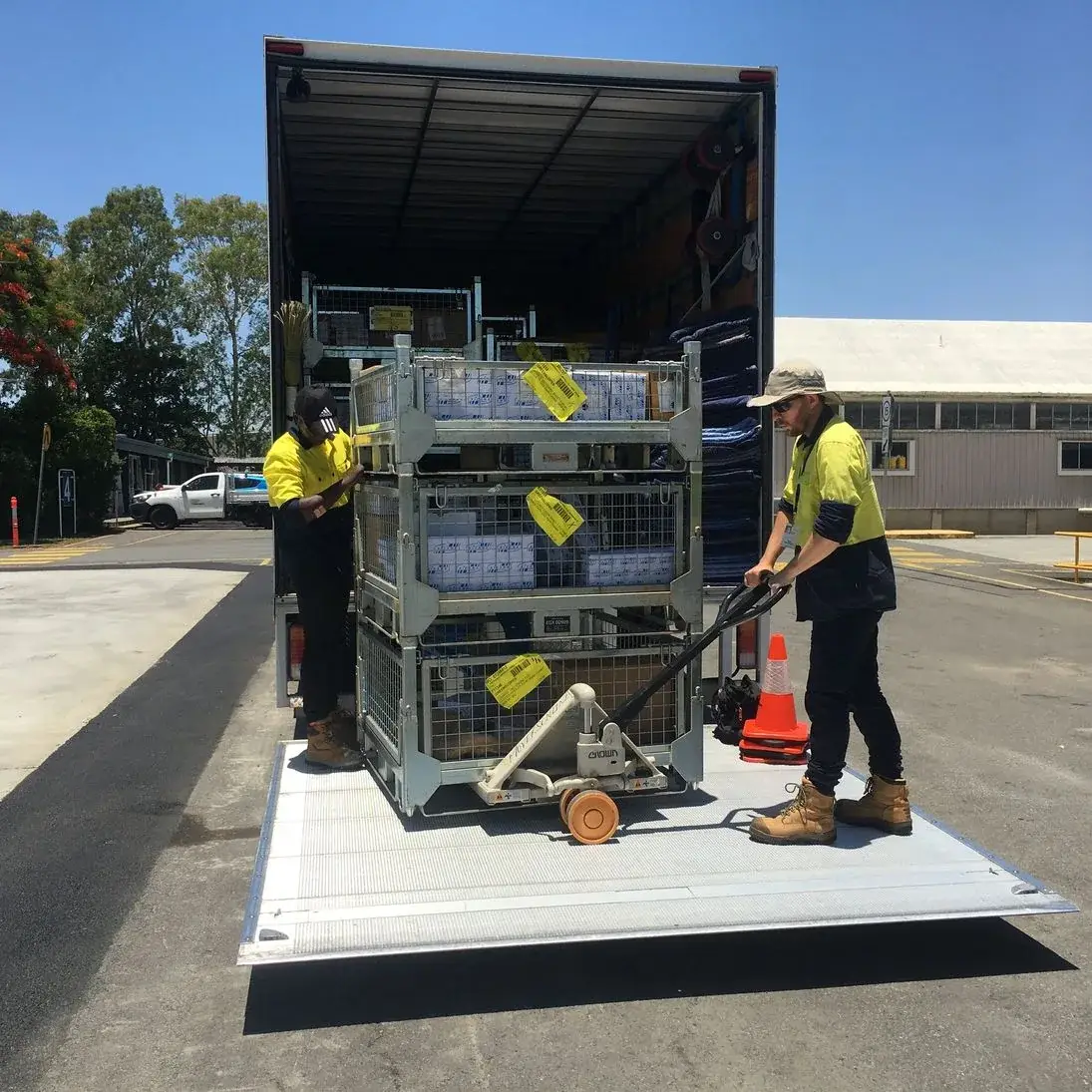 Removalists moving commercial supplies with a pallet trolley