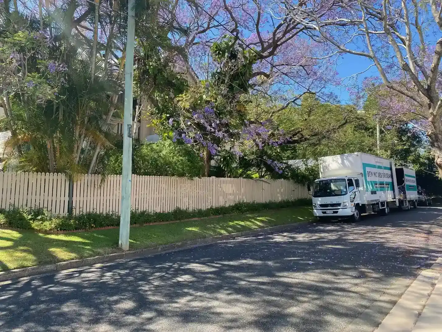 Ben Moves Brisbane trucks parked outside a Brisbane home beneath flowering jacarandas