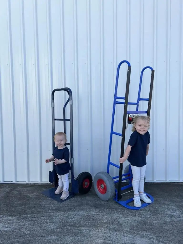 Two young children smiling and standing on moving trolleys