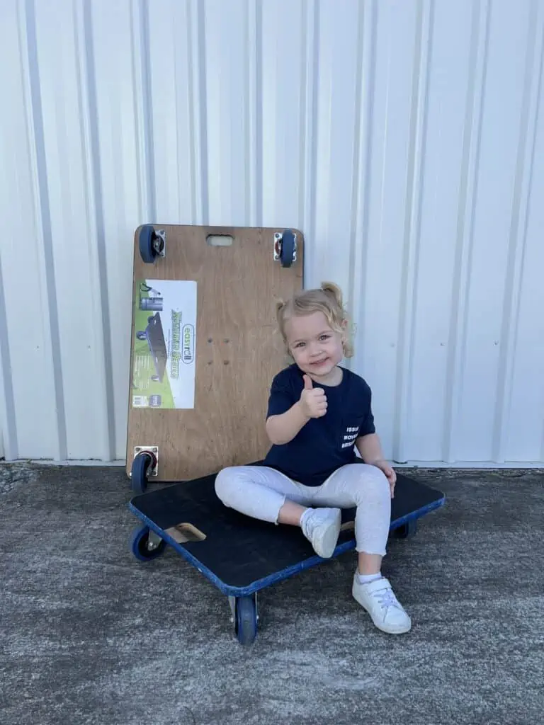 Young girl sitting on a moving trolley smiling with thumbs up